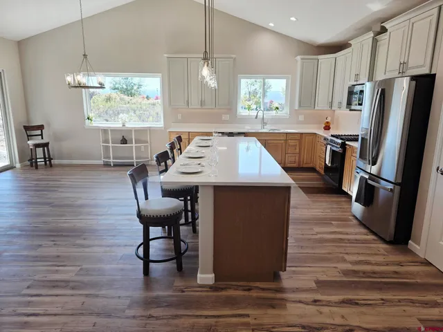 a kitchen with stainless steel appliances granite countertop a table chairs a refrigerator and a window