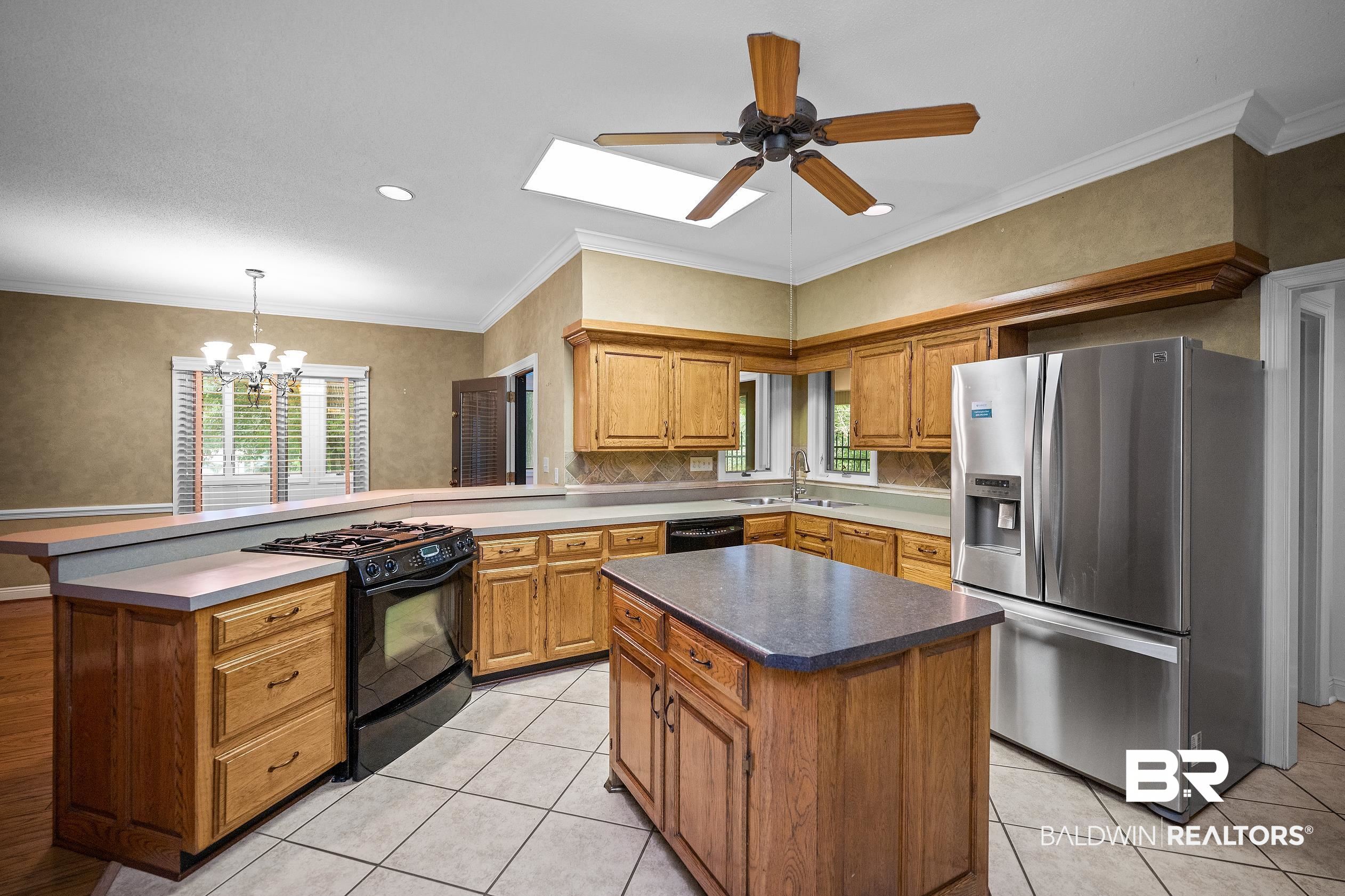 329 Norwood Road Monroeville, AL 36460 - Photo 12 of 49 Kitchen featuring wood cabinetry, stainless steel refrigerator, black range, and a central island with countertop