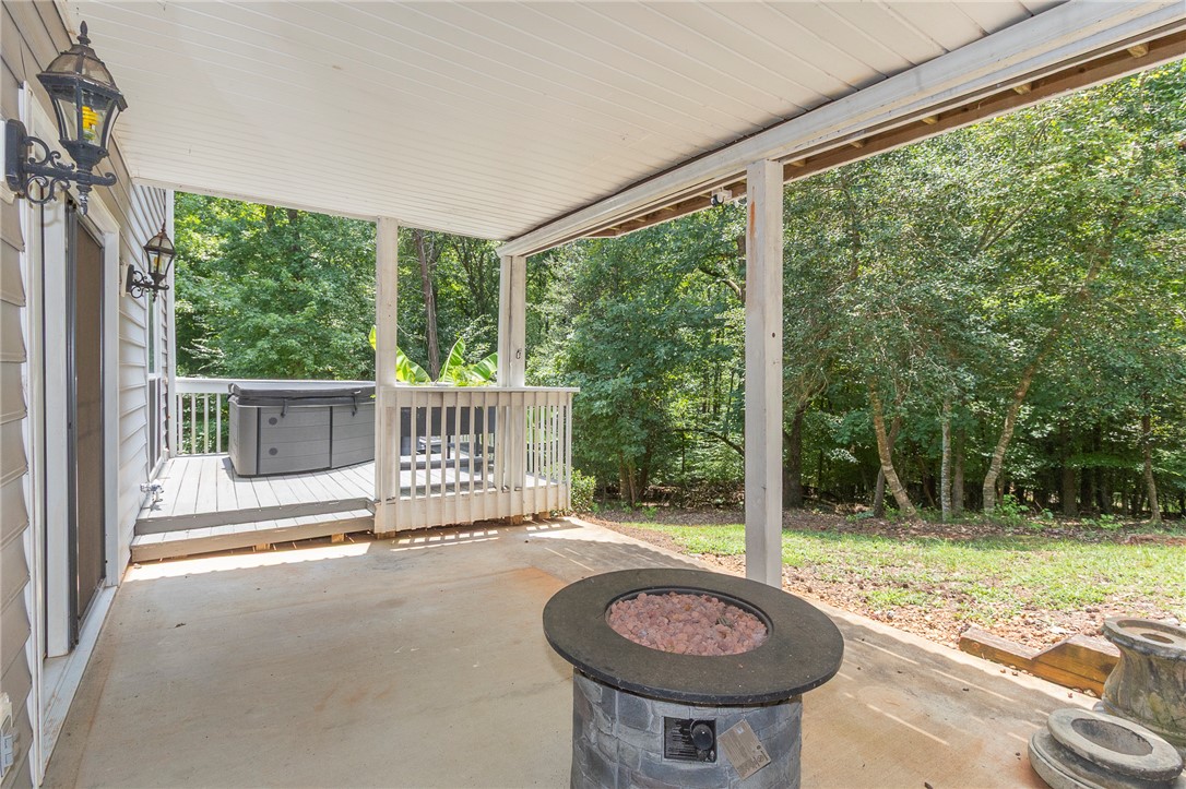 125 Inlet Pointe Drive Anderson, SC 29625 - Photo 35 of 39 A spacious covered patio features a fire pit, overlooking a hot tub on an elevated deck and a lush wooded landscape.