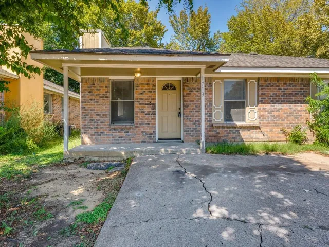 a view of a brick house with yard and plants