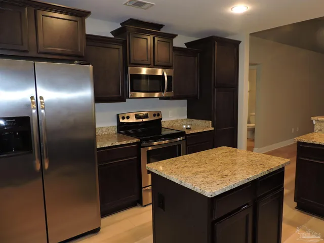 a kitchen with stainless steel appliances granite countertop a refrigerator and a stove top oven