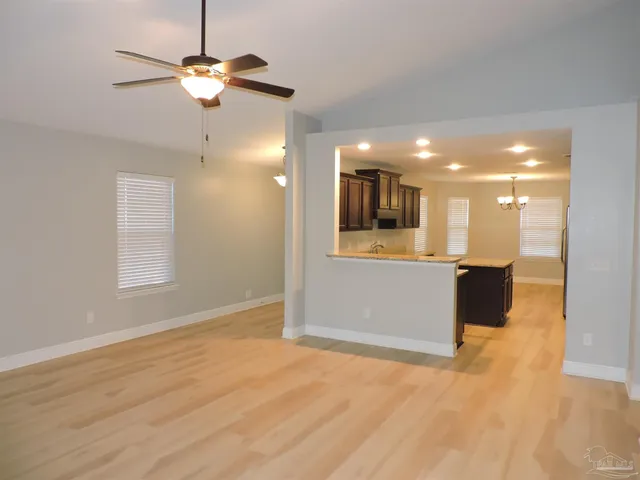 an empty room with wooden floor mirror and windows