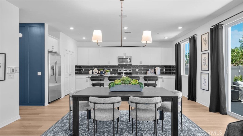 a kitchen with stainless steel appliances a dining table chairs and wooden floor
