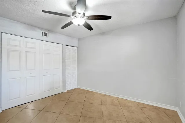 an empty room with a chandelier fan and windows