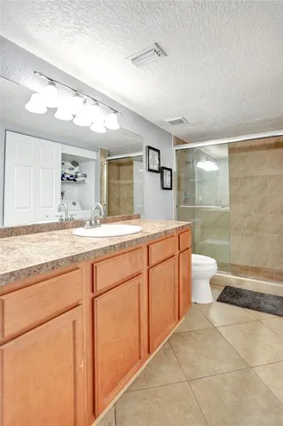 a spacious bathroom with a granite countertop sink a toilet a mirror and shower