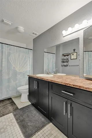 a bathroom with a granite countertop sink a toilet and a mirror