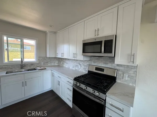 a kitchen with stainless steel appliances a sink dishwasher stove microwave and cabinets