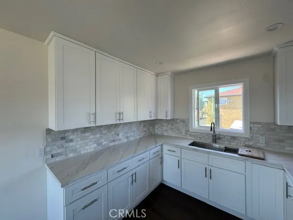 a kitchen with granite countertop white cabinets sink and window