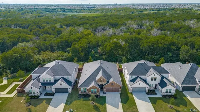 an aerial view of residential houses with outdoor space and trees