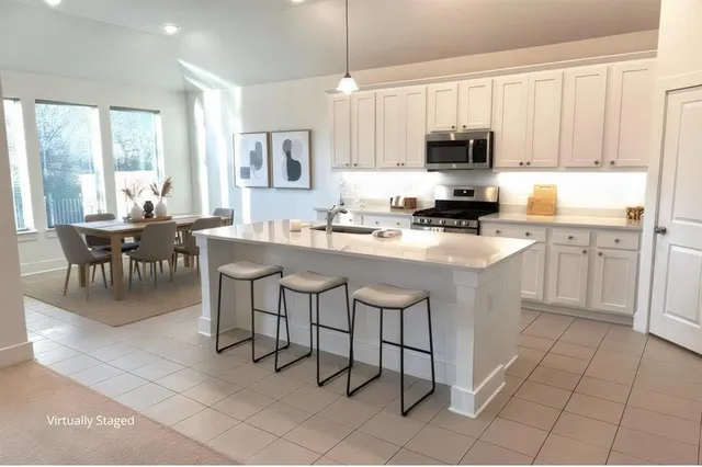 a kitchen with stainless steel appliances granite countertop a table chairs microwave and sink