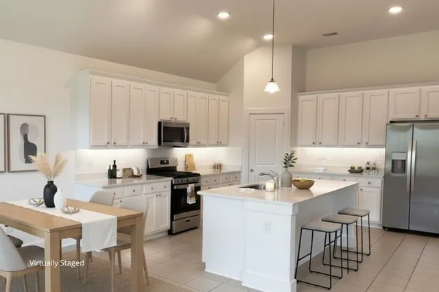 a kitchen that has a lot of white cabinets and stainless steel appliances
