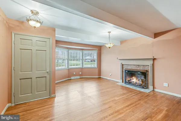 a view of an empty room with wooden floor fireplace and a window