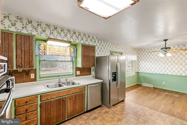 a kitchen with stainless steel appliances a sink cabinets and a large window
