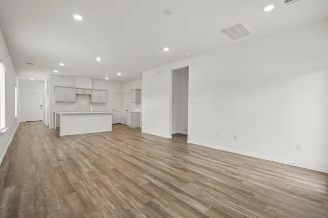 a view of kitchen and empty room with wooden floor
