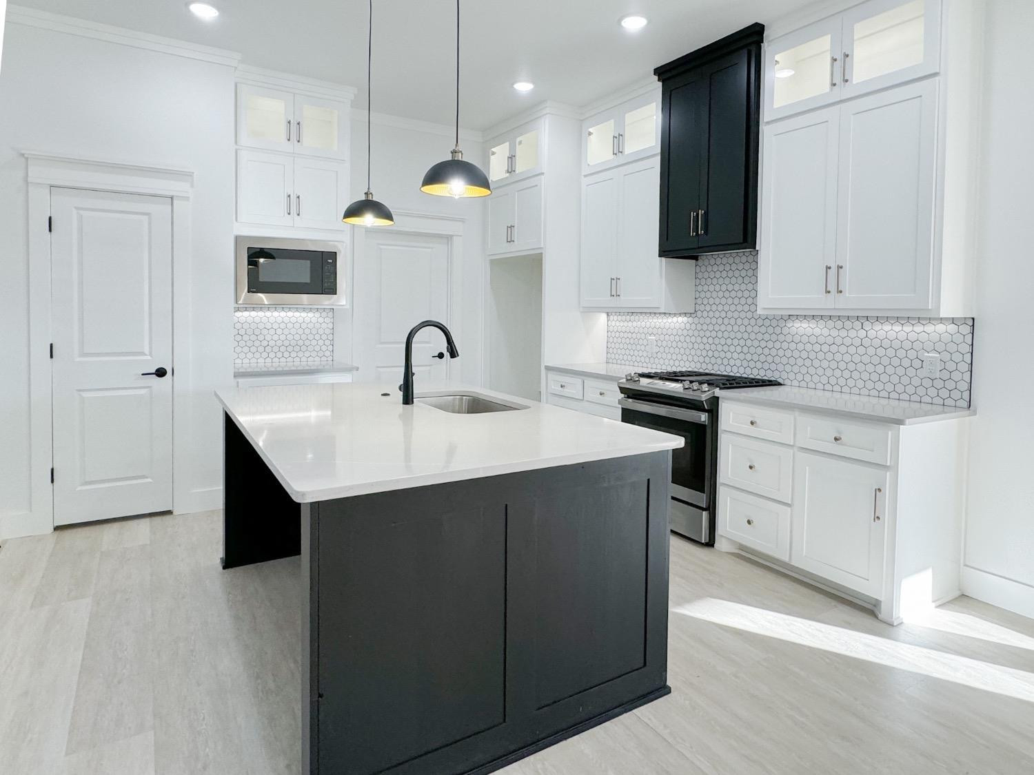 1301 Abbey Road Wolfforth, TX 79382 - Photo 9 of 24 a kitchen with a sink a stove and oven