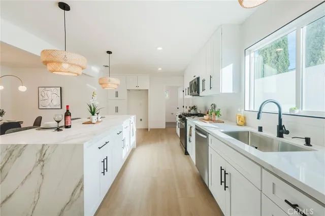 a large kitchen with kitchen island a large counter space a sink stainless steel appliances and cabinets