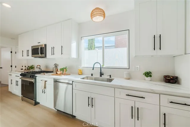 a kitchen with cabinets stainless steel appliances a sink and a window