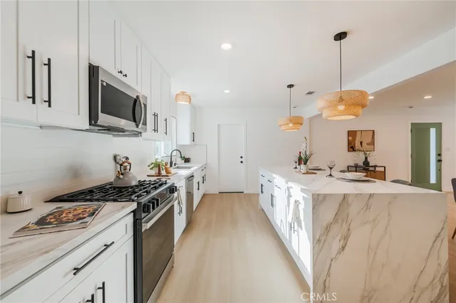 a kitchen with stainless steel appliances granite countertop a sink a stove and a wooden floors