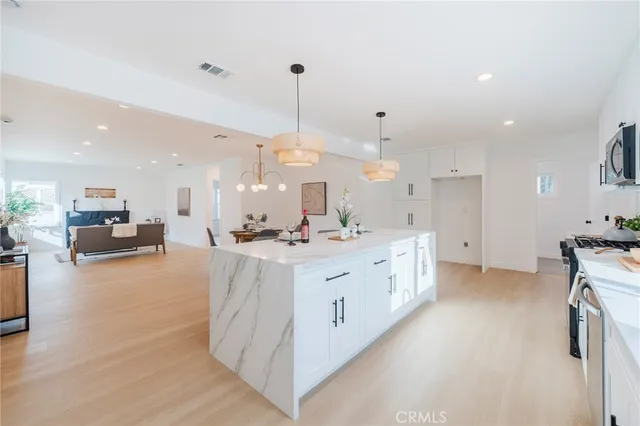 a large white kitchen with a large kitchen island white cabinets and stainless steel appliances