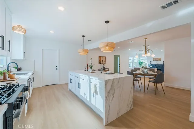 a kitchen with stainless steel appliances granite countertop a stove oven a sink dishwasher and a dining table with chairs