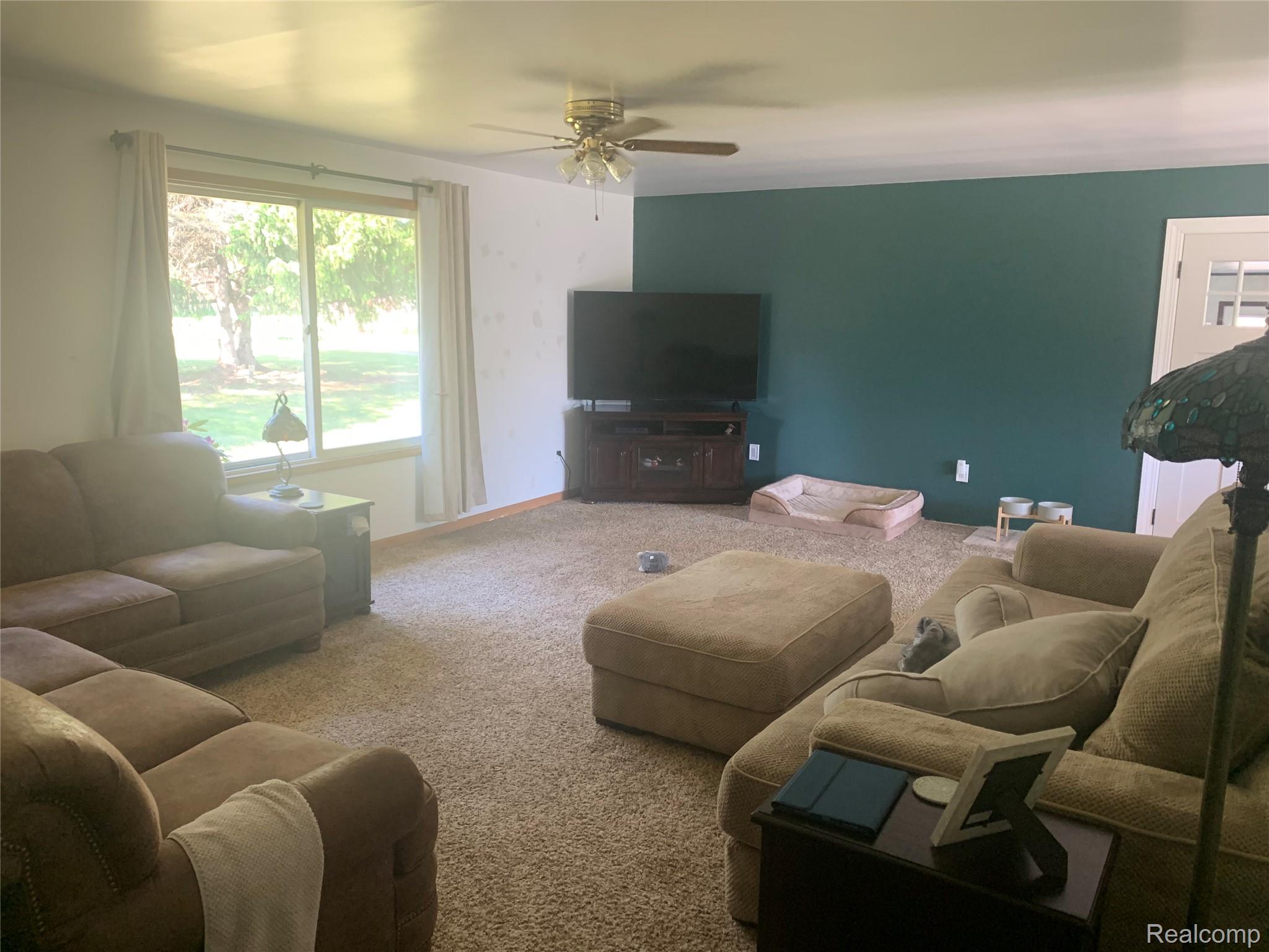 3494 Castle Road North Branch, MI 48461 - Photo 21 of 22 Carpeted living space featuring a window with natural light, a ceiling fan, a contrasting accent wall, and a door with a glass insert