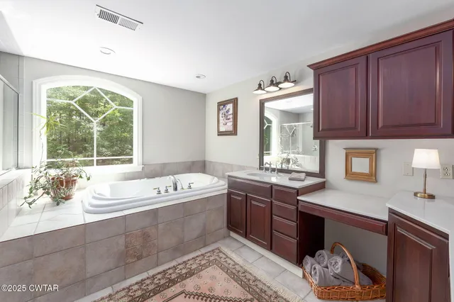 a spacious bathroom with a tub sink and mirror