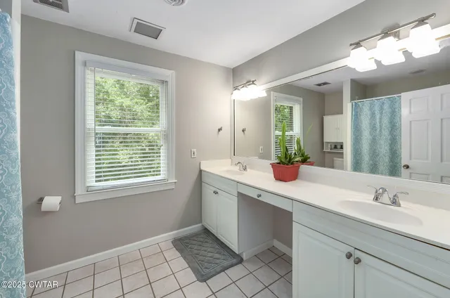 a bathroom with a double vanity sink mirror and a bathtub
