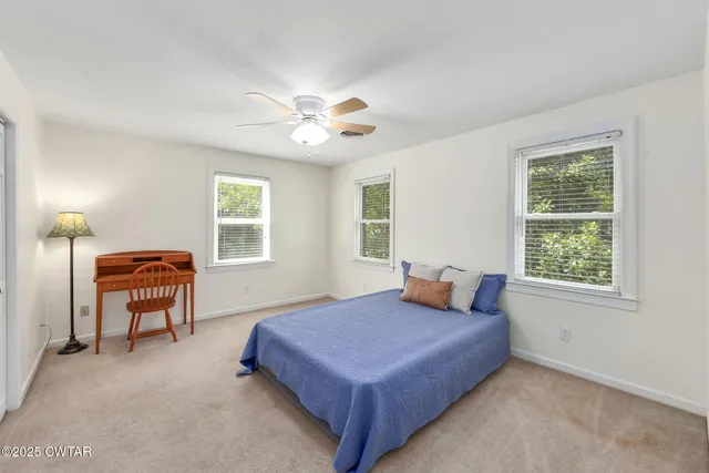 a bedroom with a large bed and two windows