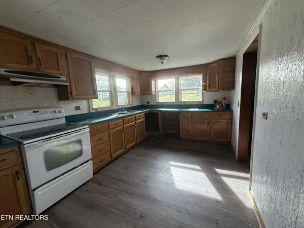 a kitchen with granite countertop a stove a sink and a refrigerator