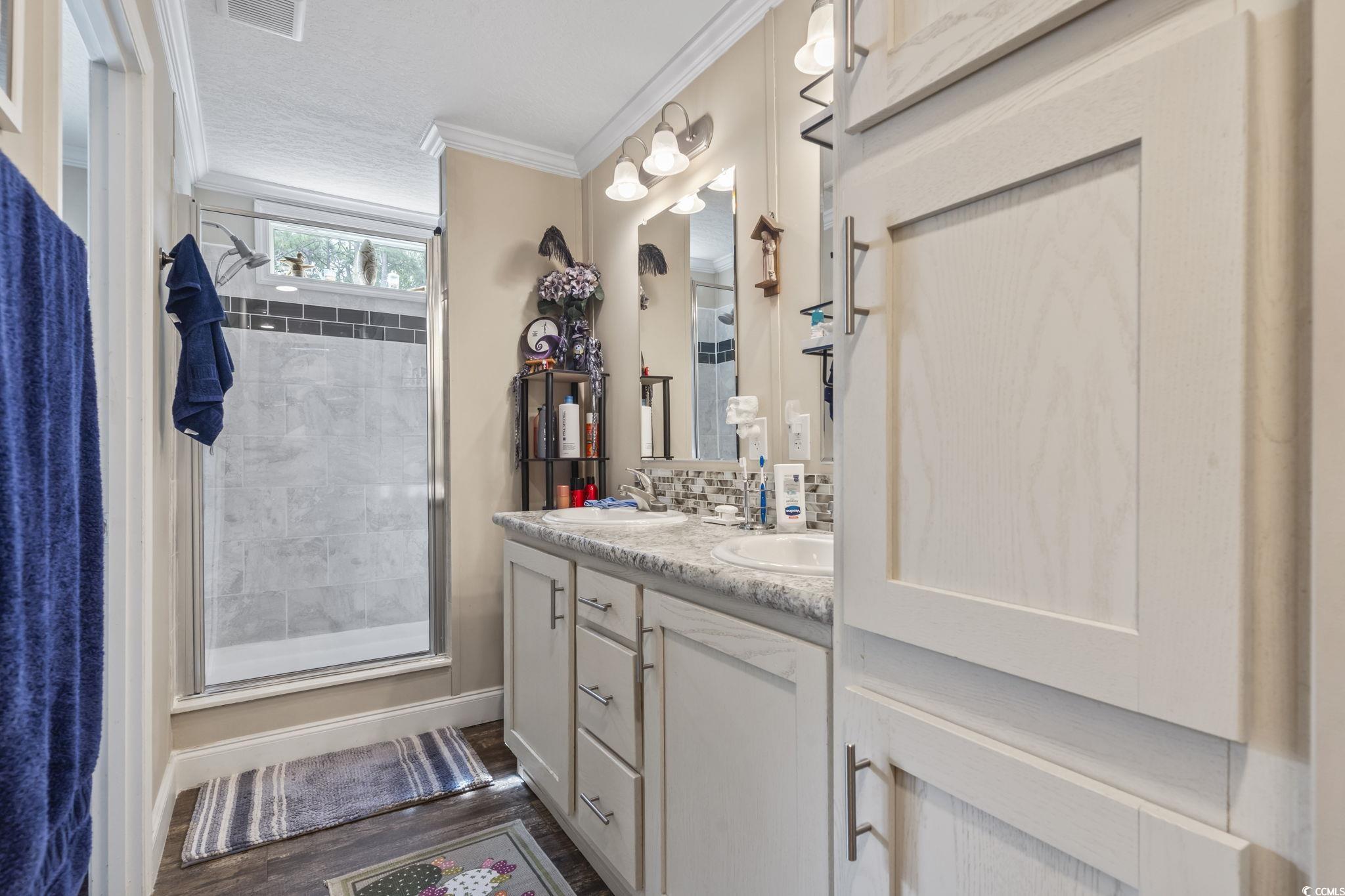 79 Offshore Drive Murrells Inlet, SC 29576 - Photo 14 of 31 Bathroom with a shower stall, double vanity, crown molding, dark wood-type flooring, and tasteful backsplash