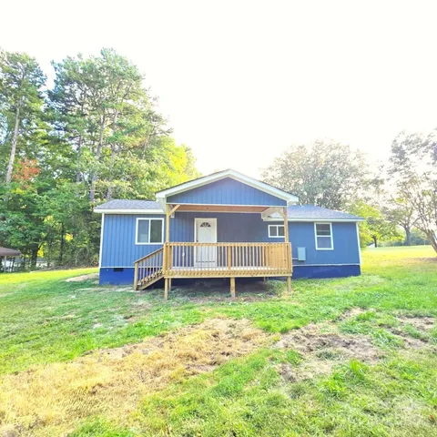 a view of a house with a yard and large tree