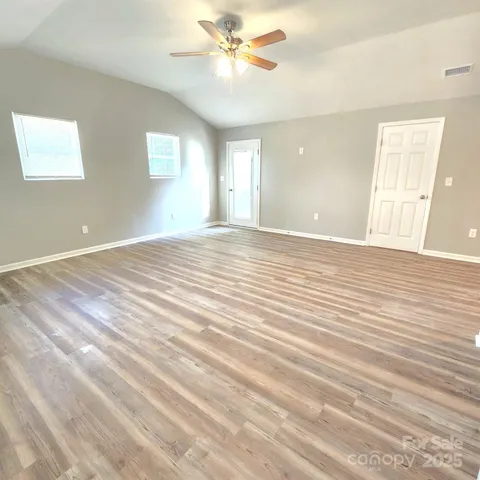 a view of an empty room with window and wooden floor