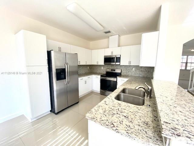 15368 Southwest 25th Terrace Miami, FL 33185 - Photo 2 of 30 a kitchen with kitchen island a sink appliances and cabinets