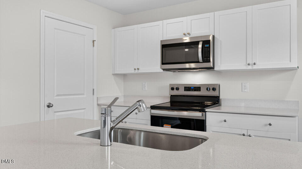 3604 Turney Drive Raleigh, NC 27610 - Photo 12 of 39 a kitchen with white cabinets and stainless steel appliances