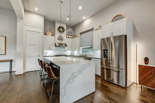 a kitchen with stainless steel appliances a refrigerator a sink dishwasher a stove and a refrigerator with wooden floor