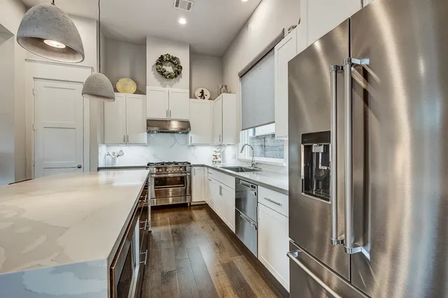 a kitchen with kitchen island a counter top space a sink stainless steel appliances and cabinets