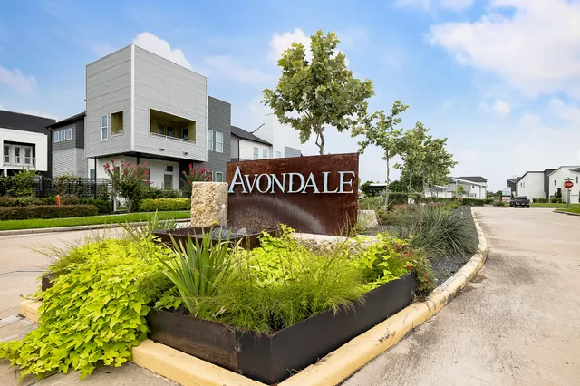 a view of a sign board with buildings in the background