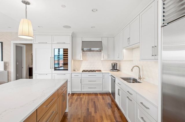 a kitchen with granite countertop a sink cabinets stainless steel appliances and a window