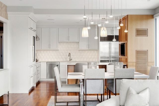 a kitchen with stainless steel appliances kitchen island granite countertop a dining table chairs and white cabinets