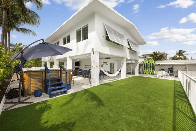 a view of a patio with table and chairs under an umbrella with palm trees
