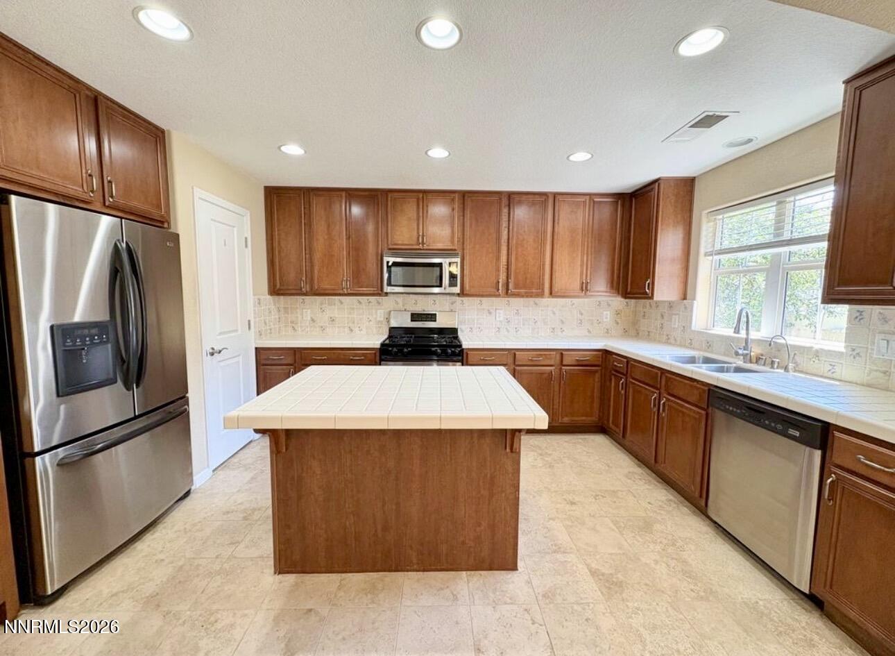 7616 Stone Bluff Way Reno, NV 89523 - Photo 4 of 18 a kitchen with kitchen island granite countertop wooden cabinets a refrigerator and a sink