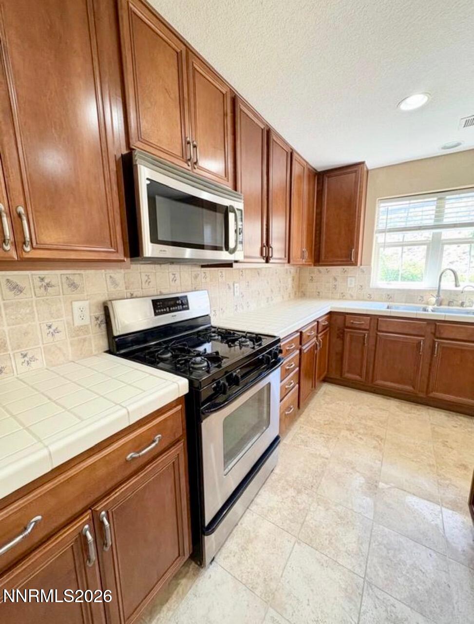 7616 Stone Bluff Way Reno, NV 89523 - Photo 5 of 18 a kitchen with stainless steel appliances a sink dishwasher stove and microwave