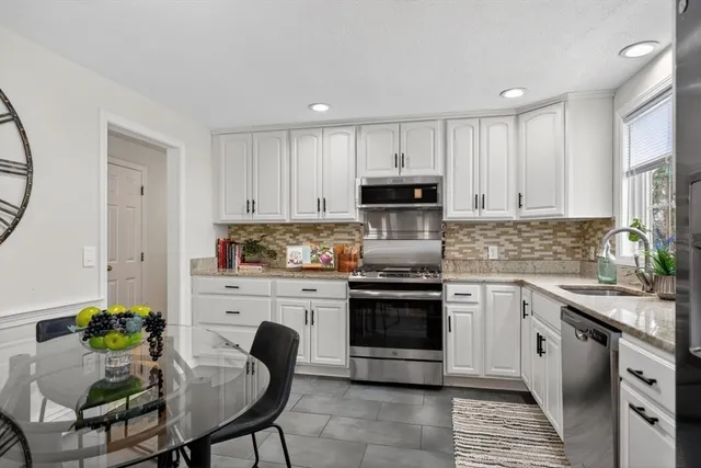 a kitchen with kitchen island granite countertop a sink stove and white cabinets