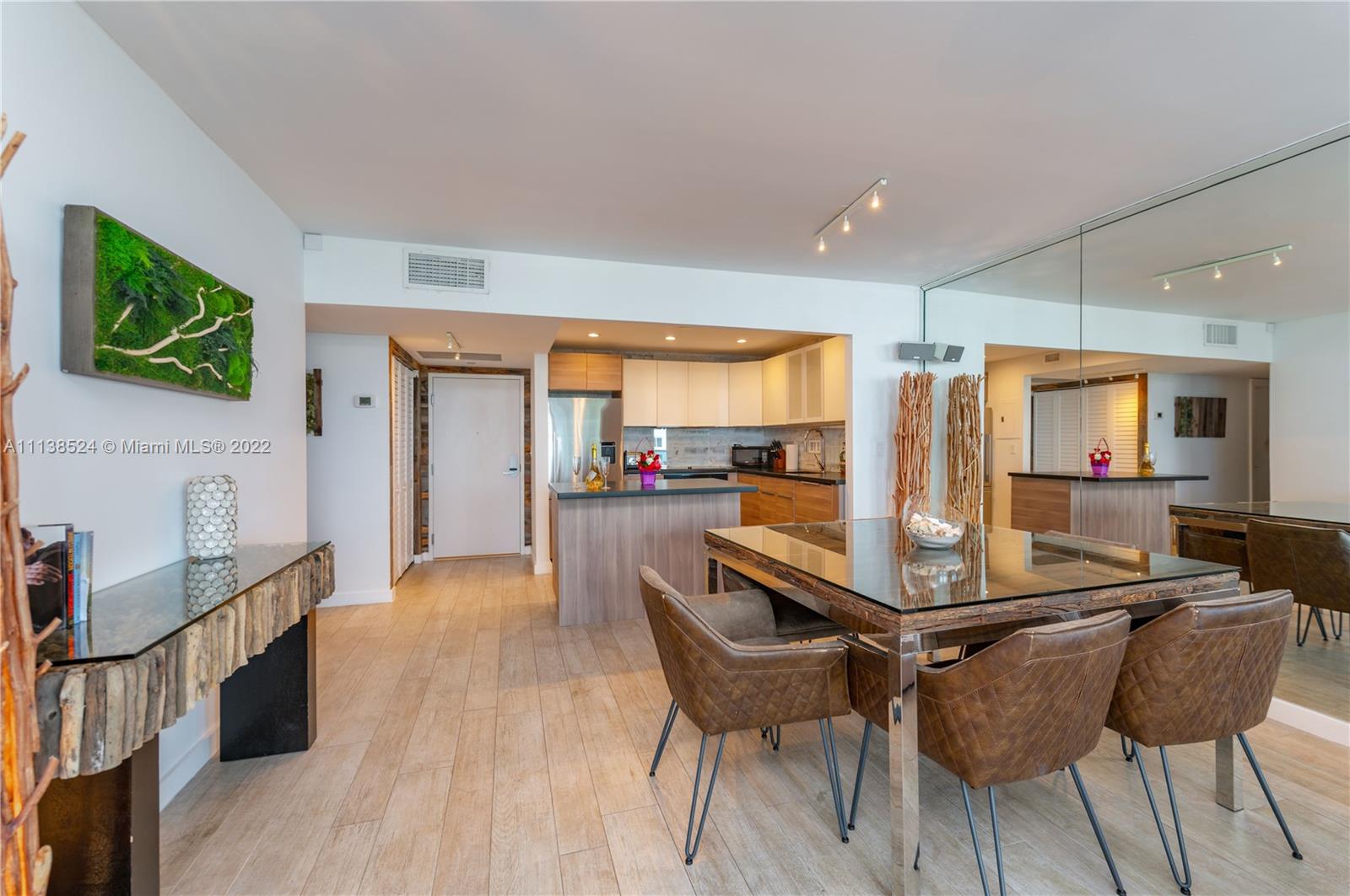 Mid Beach Miami Beach, FL 33139 - Photo 3 of 18 a kitchen with stainless steel appliances kitchen island granite countertop a stove a refrigerator a sink a dining table and chairs with wooden floor