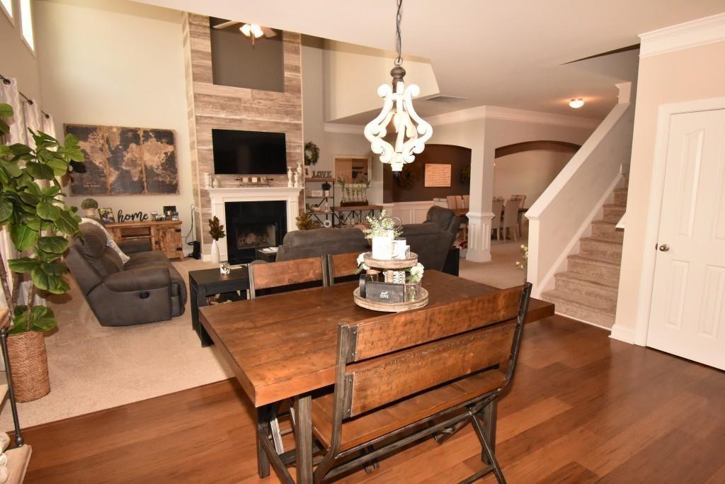 5691 Apple Grove Road Northeast Buford, GA 30519 - Photo 16 of 23 a living room with furniture a fireplace and a dining table with wooden floor