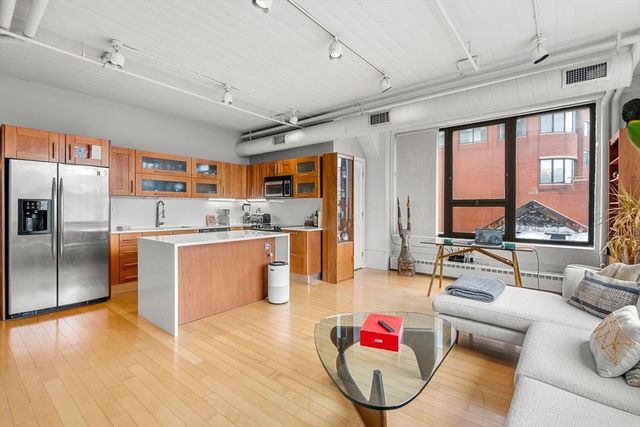 a kitchen with stainless steel appliances kitchen island granite countertop a refrigerator a stove and a sink with couches