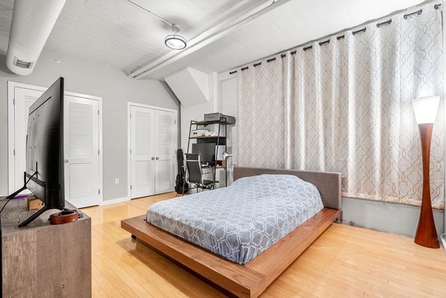 a bedroom with a bed window and a flat tv screen