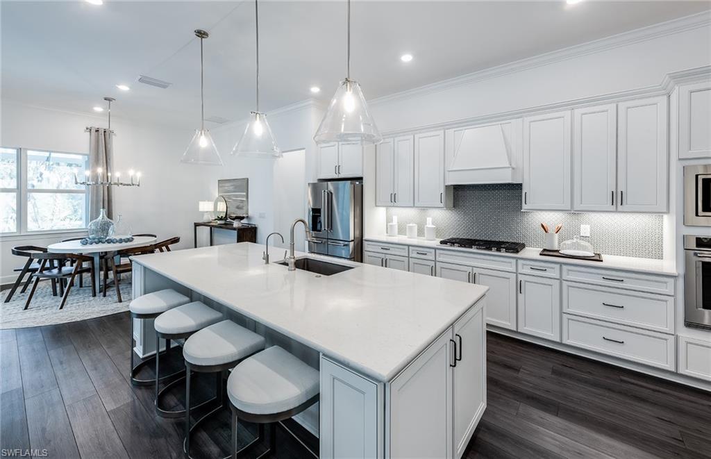 18239 Parksville Drive Estero, FL 33928 - Photo 7 of 38 a kitchen with a table chairs stove a sink dishwasher and cabinets with wooden floor