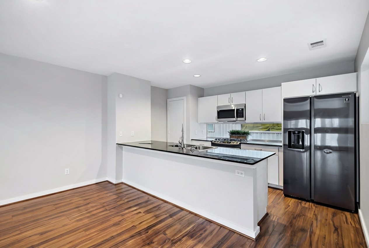 2605 Calumet Street, Unit 34 Houston, TX 77004 - Photo 20 of 37 a kitchen with stainless steel appliances granite countertop a refrigerator a stove top oven a sink and dishwasher with wooden floor
