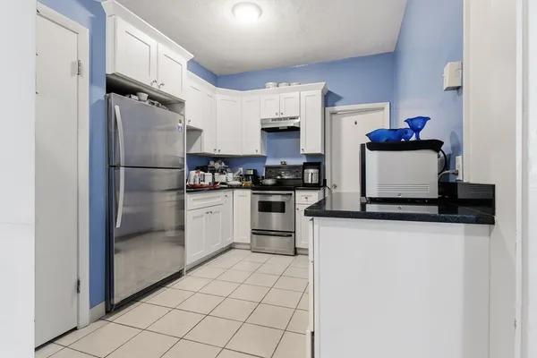 a kitchen with stainless steel appliances granite countertop a refrigerator sink stove and white cabinets
